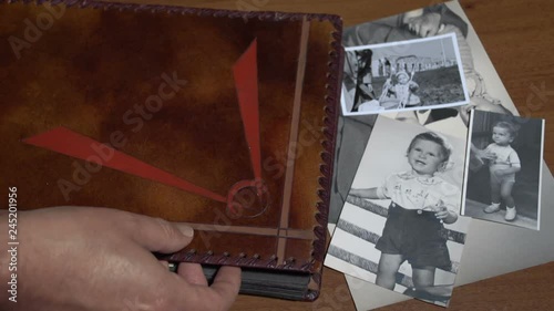 A man is leafing through a vintage photo album to look for old memory and nostalgia of lost childhood FDV