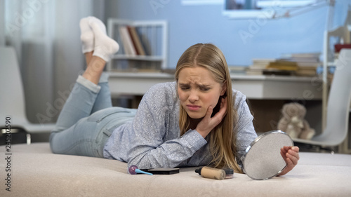 Young lady lying on bed, worried about her skin problems, age-related changes