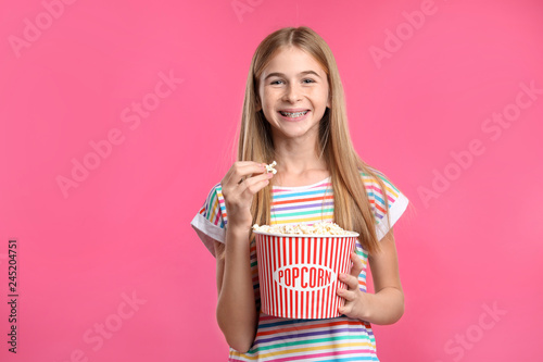 Teenage girl with popcorn during cinema show on color background