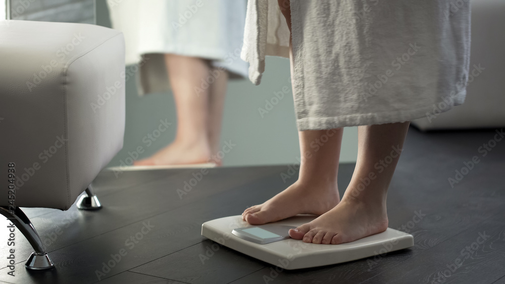 Healthy dieting, woman standing on scales to see result, normal weight range Healthy dieting, woman standing on scales to see result, normal weight range