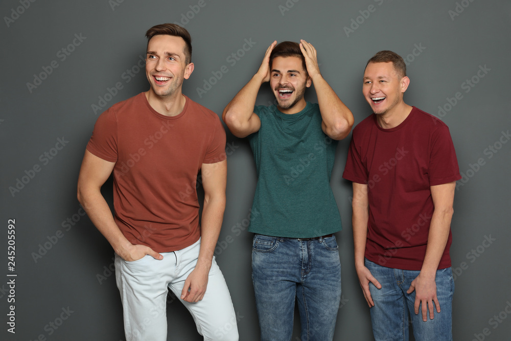 Group of friends laughing together against gray background Group of friends laughing together against gray background