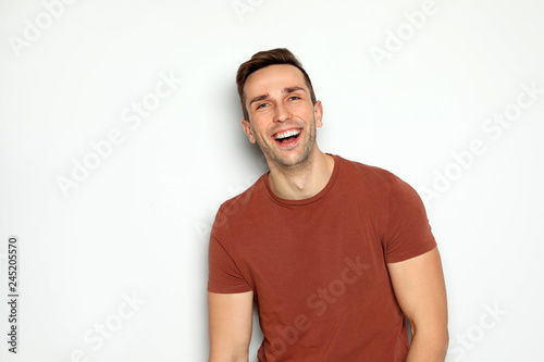 Billede på lærred Portrait of handsome man laughing against light background