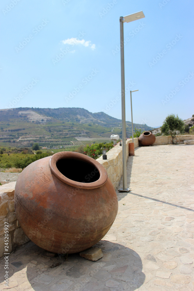 Amazing green bright landscape on the background of the mountains, with ancient clay barrels for the manufacture and storage of wine. Cyprus, Paphos Amazing green bright landscape on the background of the mountains, with ancient clay barrels for the manufacture and storage of wine. Cyprus, Paphos