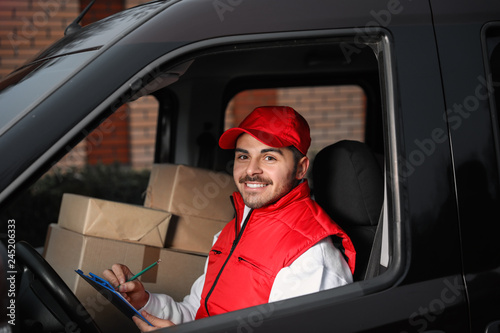 Deliveryman with clipboard and parcels in car