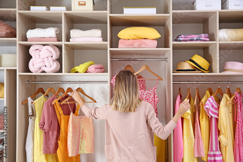 Woman choosing clothes from large wardrobe closet photo