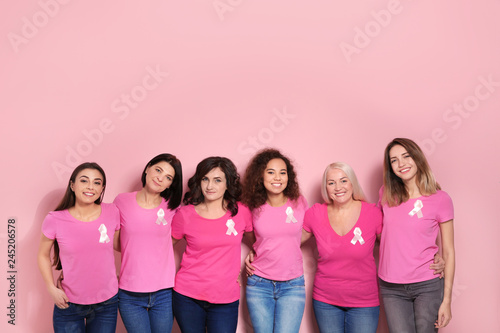 Group of women with silk ribbons on color background. Breast cancer awareness concept