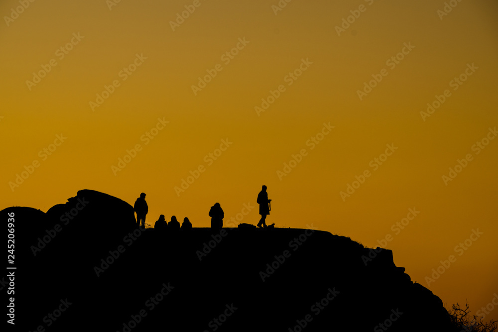 silhouette of people on top of a mountain at sunset with orange sky