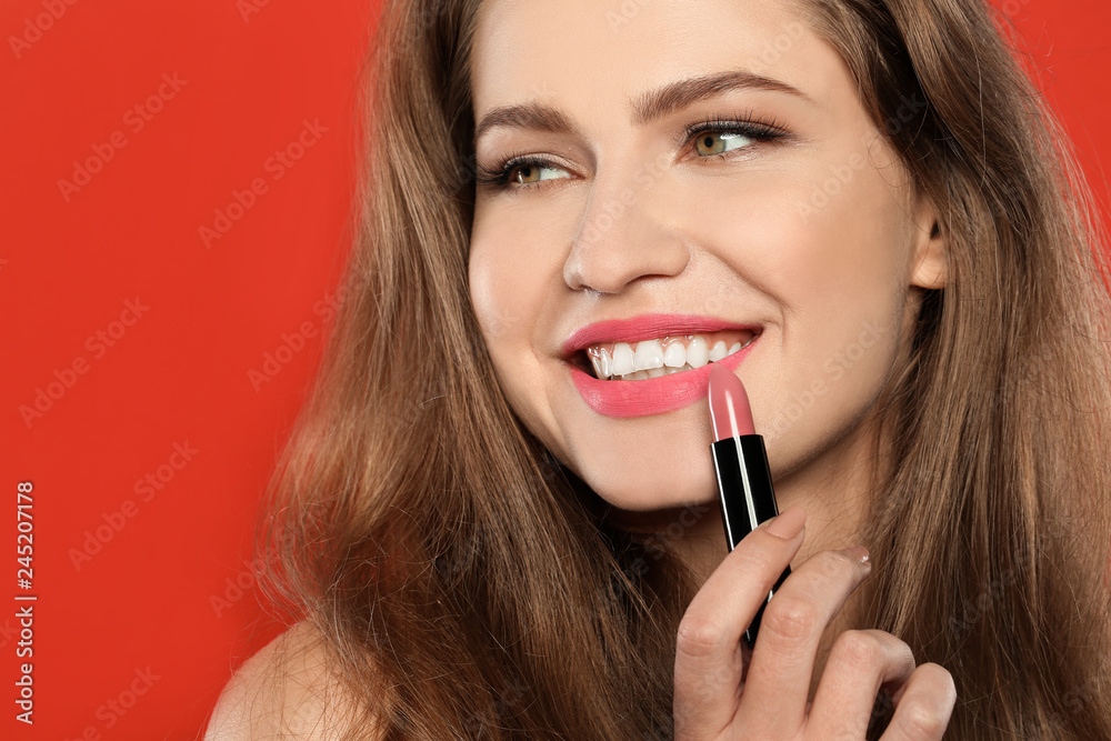 Young woman applying beautiful lipstick on color background Young woman applying beautiful lipstick on color background
