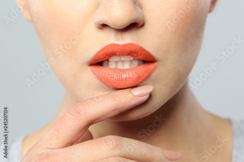 Young woman wearing beautiful lipstick on gray background, closeup