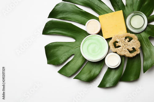 Composition with body care products  wisp and green leaf on white background  top view. Space for text