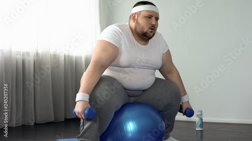 Weak obese male struggling to lift dumbbells, lack of physical activity, diet