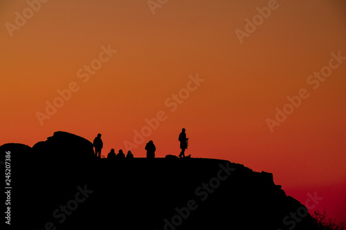 silhouette of people on top of a mountain at sunset with red sky