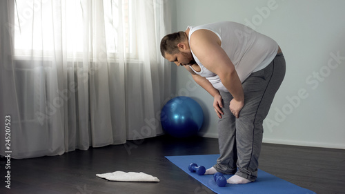 Lazy unmotivated man throwing dumbbells on floor, hopelessness, insecurities
