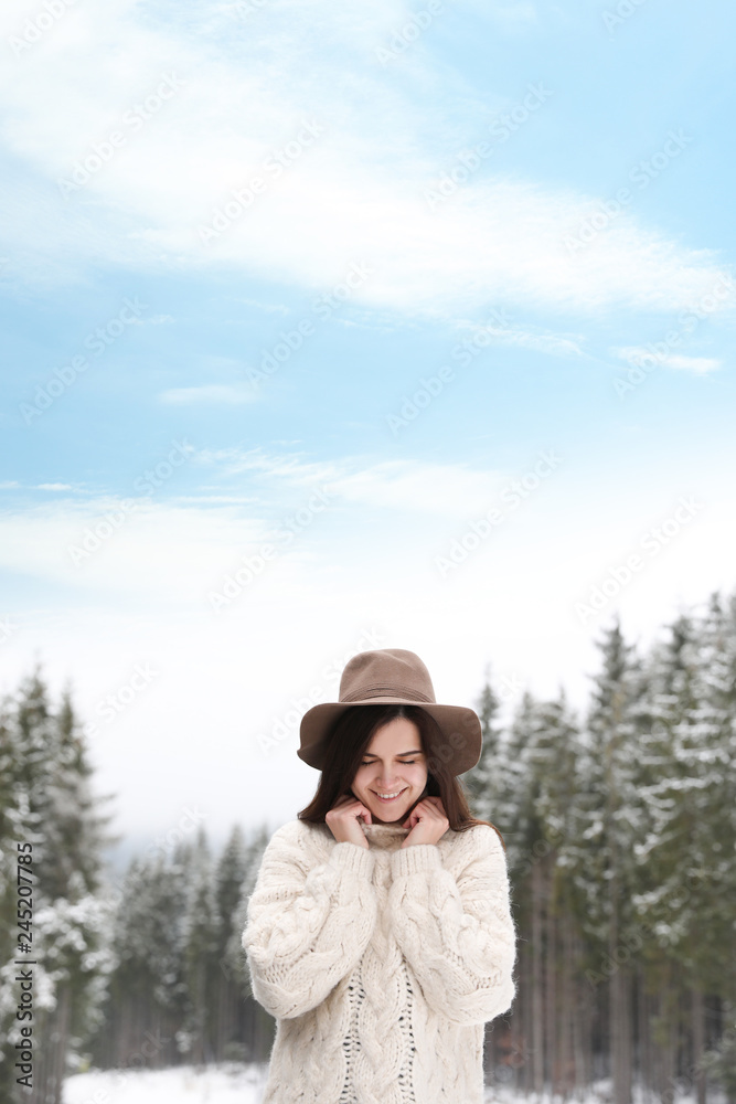 Young woman in warm sweater near snowy forest. Winter vacation Young woman in warm sweater near snowy forest. Winter vacation