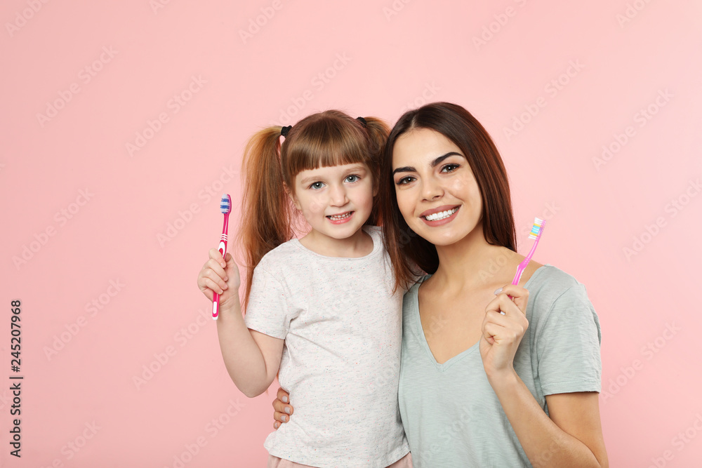 Little girl and her mother with toothbrushes on color background. Teeth care Little girl and her mother with toothbrushes on color background. Teeth care