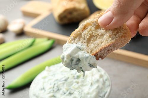 Tableau sur toile Woman dipping bread in cucumber sauce on blurred background