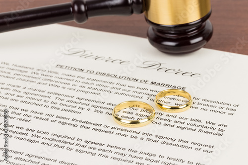Wooden judge gavel, golden rings, and divorce decree; document is mock-up