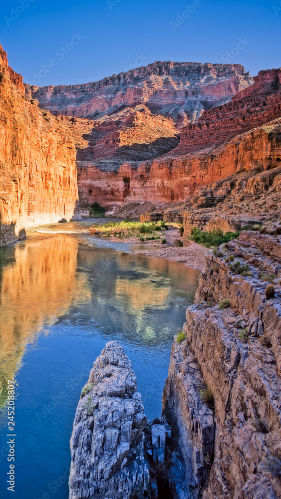 Colorado River flows past canyon walls of Marble Canyon near the outflow of South Canyon in late afternoon