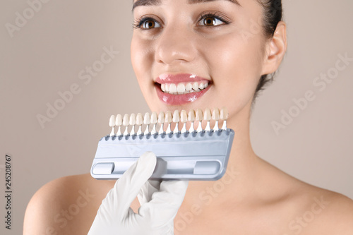 Dentist checking young woman's teeth color, closeup