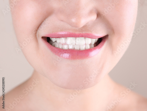 Young woman with beautiful smile on color background  closeup