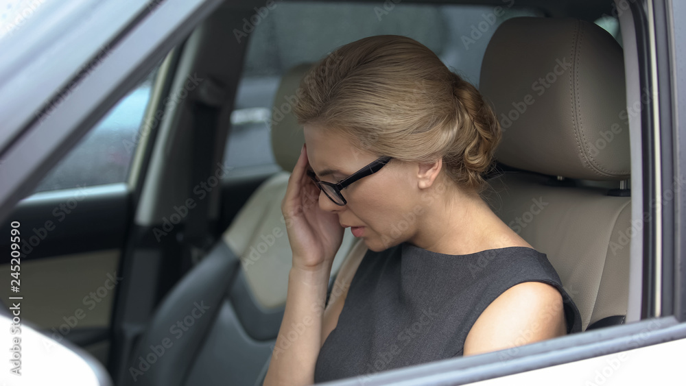Woman in car suffering from throbbing headache, stress and overworking result