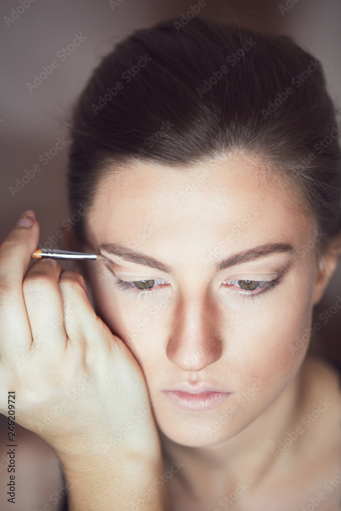 Young beautiful woman applying make-up by make-up artist. Process of making makeup.