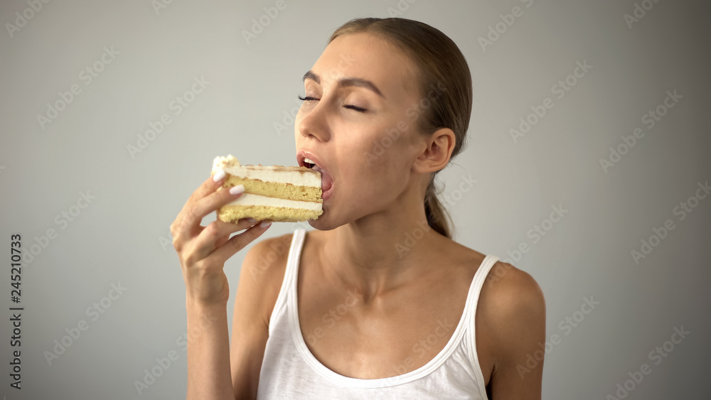 Beautiful woman enjoying delicious cake, sugar temptation, diabetes risk Beautiful woman enjoying delicious cake, sugar temptation, diabetes risk