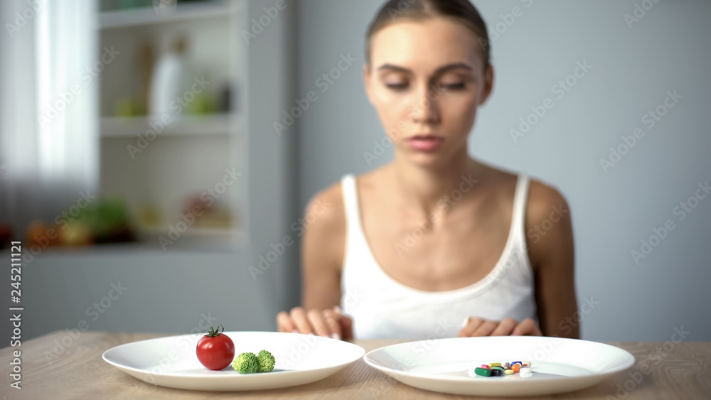 Anorexic girl choosing weight loss drugs instead of vegetables, unhealthy diet Anorexic girl choosing weight loss drugs instead of vegetables, unhealthy diet