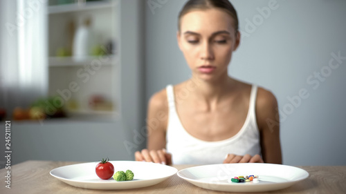 Anorexic girl choosing weight loss drugs instead of vegetables  unhealthy diet
