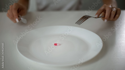 Lady eating pill instead of food, anti-obesity drug, severe starvation, problem photo