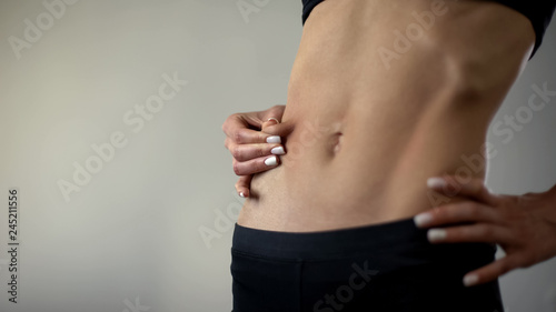 Tableau sur toile Anorexic girl stretching skin, no fat layer, weight loss affects health, closeup