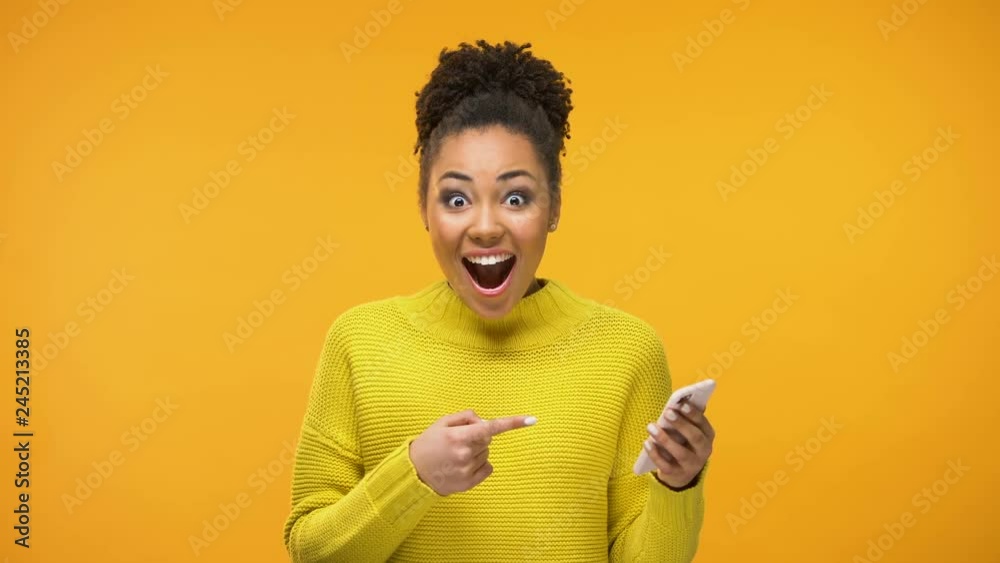 African-American woman using smartphone, excited about job acceptance e-mail