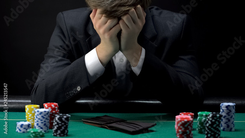Fotografie, Obraz Young devastated businessman losing poker game at casino, gambling addiction