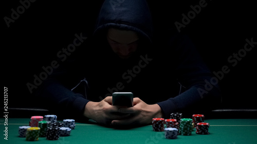 Bild auf Leinwand Anonymous male playing online game on smartphone app, illegal business, addict