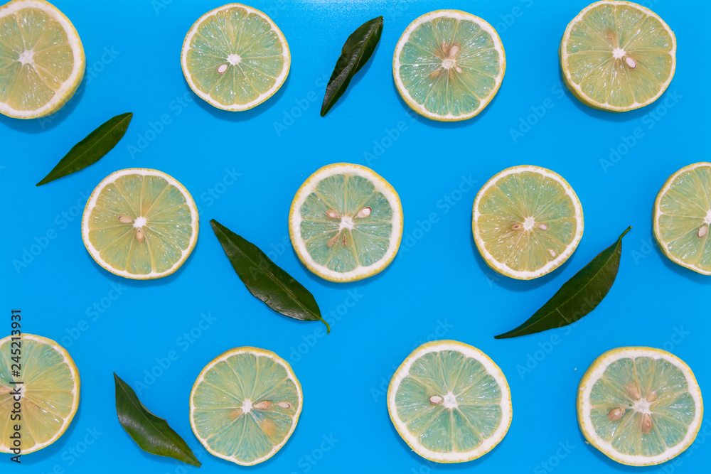 Lemon slices with leaves on blue background, flat lay image. Lemon slices with leaves on blue background, flat lay image.
