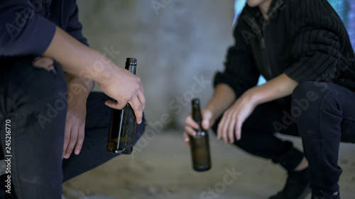 Drunkards holding beer bottles resting in abandoned house, social issue, problem