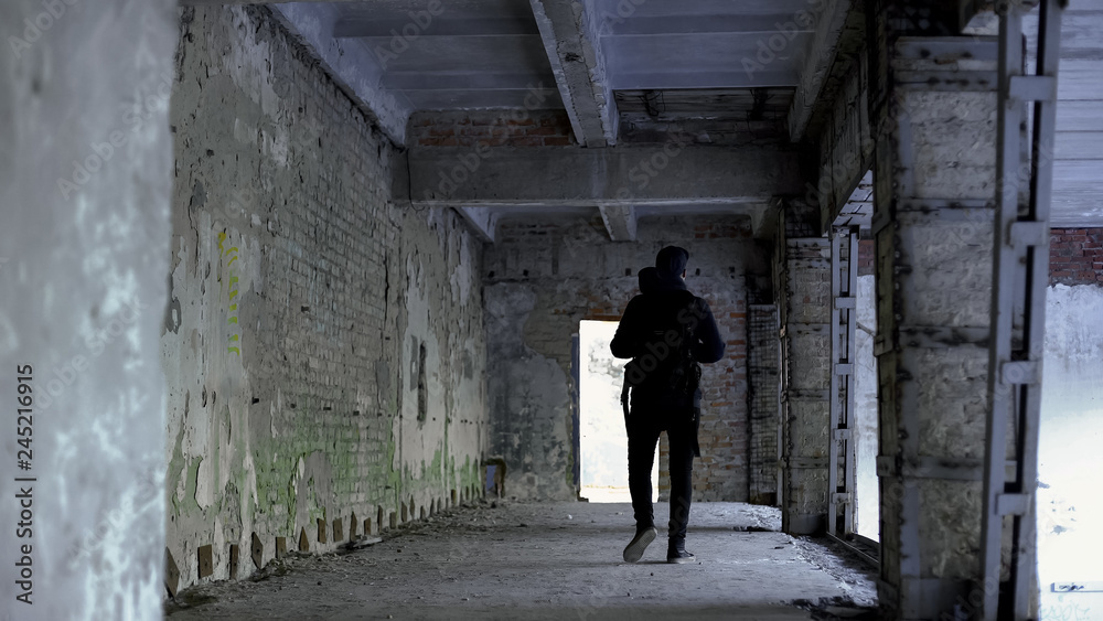 Teenage guy walking in dangerous place, abandoned house, risk of kidnapping