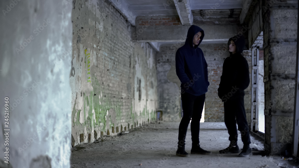 Boys in hoodie talking in ruined building, teenage gang, young criminals Boys in hoodie talking in ruined building, teenage gang, young criminals