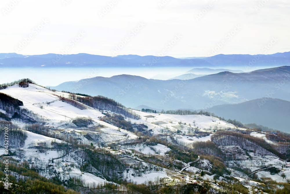 Snow-covered mountainside on the background of other mountain ranges on a sunny winter day.