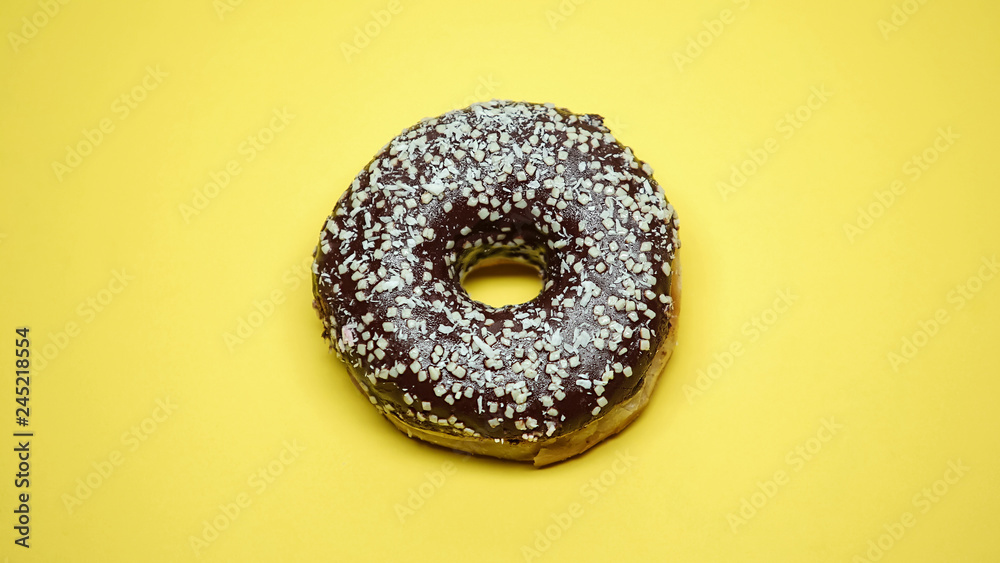 Delicious chocolate donut on yellow background, confectionery shop, macro shot Delicious chocolate donut on yellow background, confectionery shop, macro shot