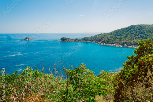  Scenic view of Shark Bay on Koh Tao island, Thailand. Turquoise sea, lush green hills, and peaceful tropical landscape under clear blue sky. Perfect summer travel destination.