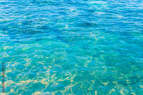  Crystal clear turquoise sea water with sunlight reflections on the surface. Tropical ocean background from Koh Tao, Thailand.
