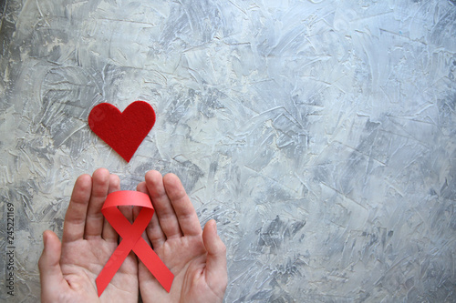 man's hands hold a red ribbon.hiv awareness concept, world AIDS day photo