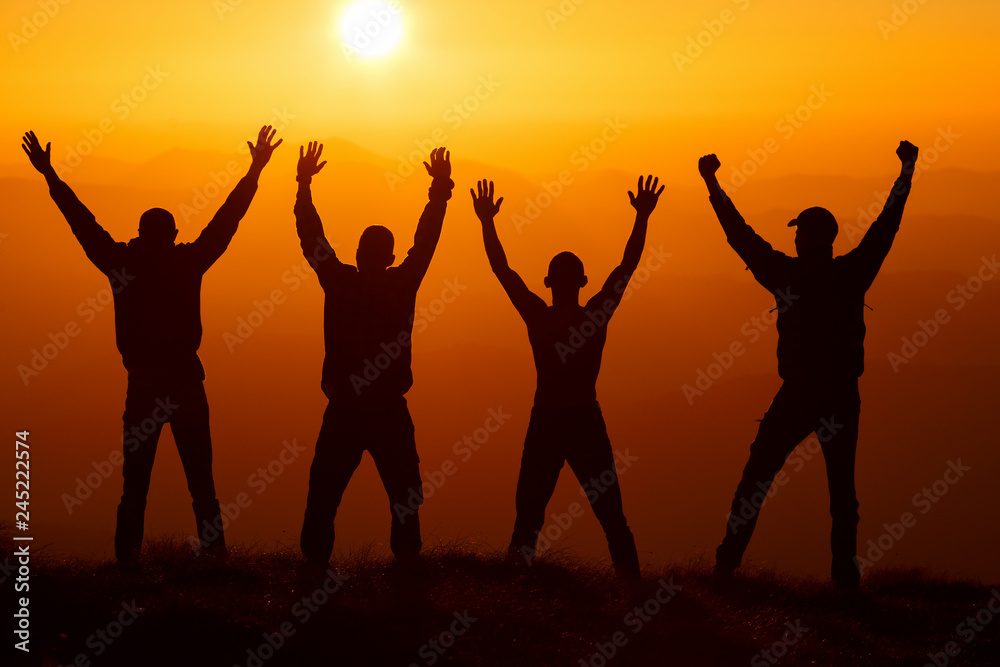 Silhouette group of hikers greetings sun with raised hands against sunset. Hikers walking on a mountain at sunset. Silhouette group of hikers greetings sun with raised hands against sunset. Hikers walking on a mountain at sunset.