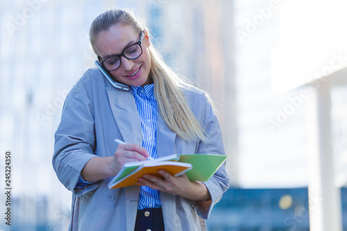 Business woman talking on the phone and writing in a notebook
