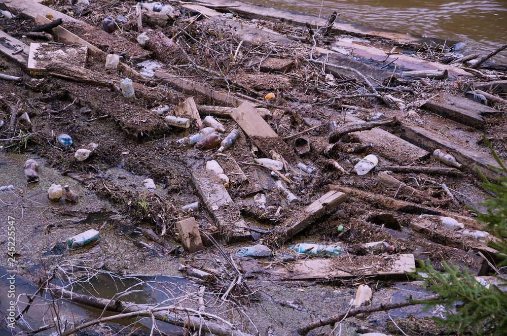 On the water surface nailed to the shore a lot of different debris: used items, fragments of boards, sticks, plant debris, instagram. On the water surface nailed to the shore a lot of different debris: used items, fragments of boards, sticks, plant debris, instagram.