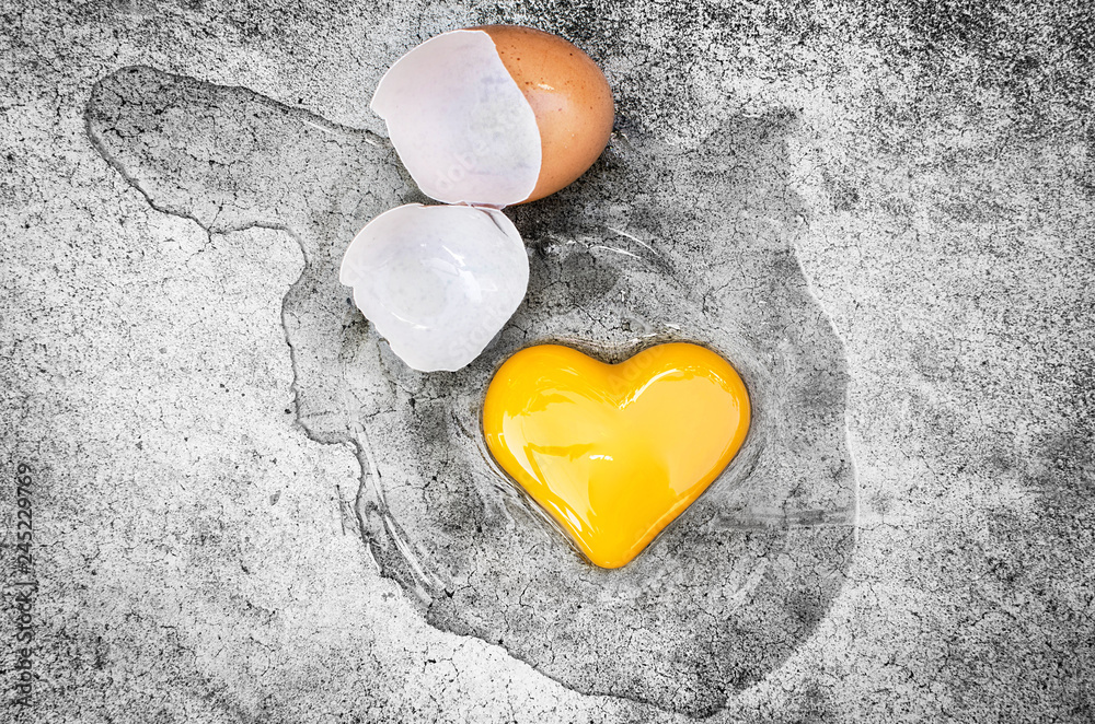 Obraz premium Heart Shape Egg Yolk with eggshells on the ground. Concept Valentines Day