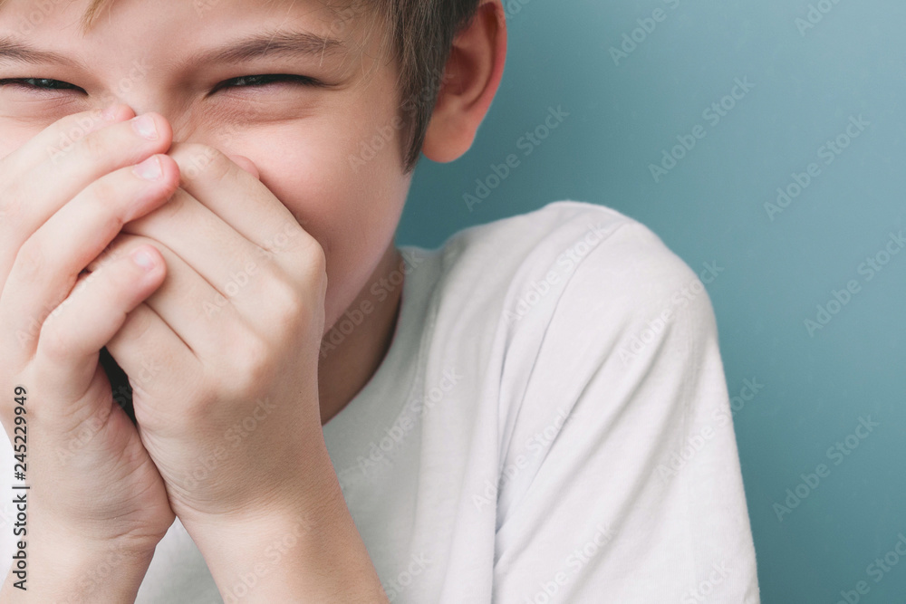 Laughing boy covers his mouth with his hands Laughing boy covers his mouth with his hands