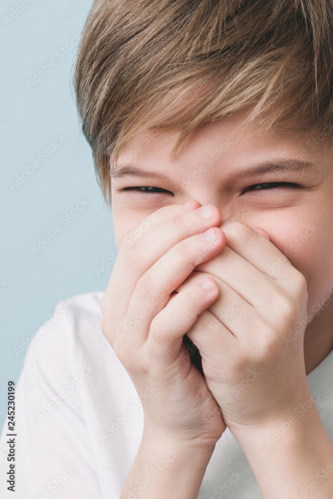 Laughing boy covers his mouth with his hands Laughing boy covers his mouth with his hands