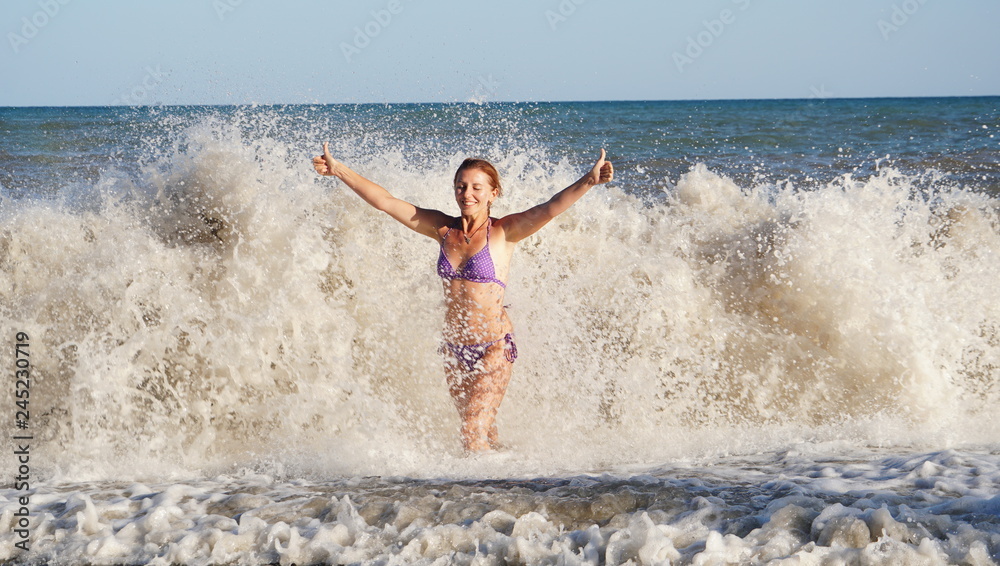 Fototapeta premium Beautiful young woman in surf waves on the beach